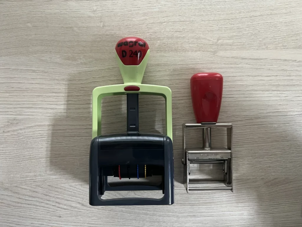 Dwa stempelki na biurowym blacie, różnej wielkości, z plastikowym i metalowym uchwytem.