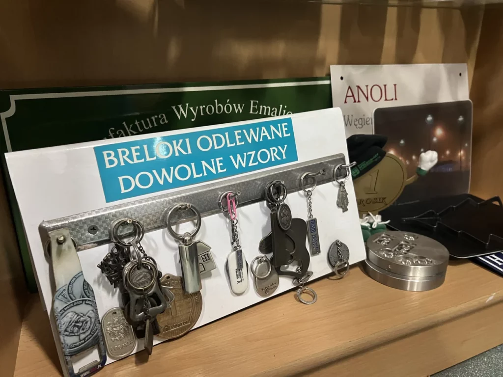 Breloki odlewane w różnych wzorach na ekspozytorze, z metalowymi elementami do użytku reklamowego.