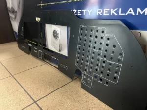 Panel kontrolny z metalu z wycięciami i oznaczeniami technicznymi, przygotowany do montażu w systemach awionicznych.